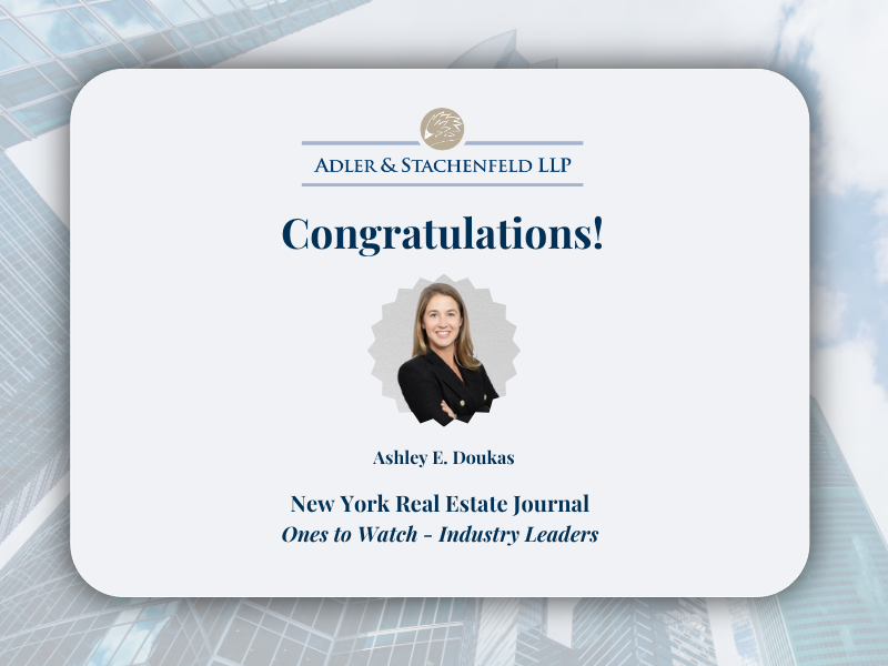Adler & Stachenfeld LLP congratulatory graphic recognizing Ashley E. Doukas for being named to New York Real Estate Journal’s “Ones to Watch – Industry Leaders” list, featuring her headshot on a cityscape background.